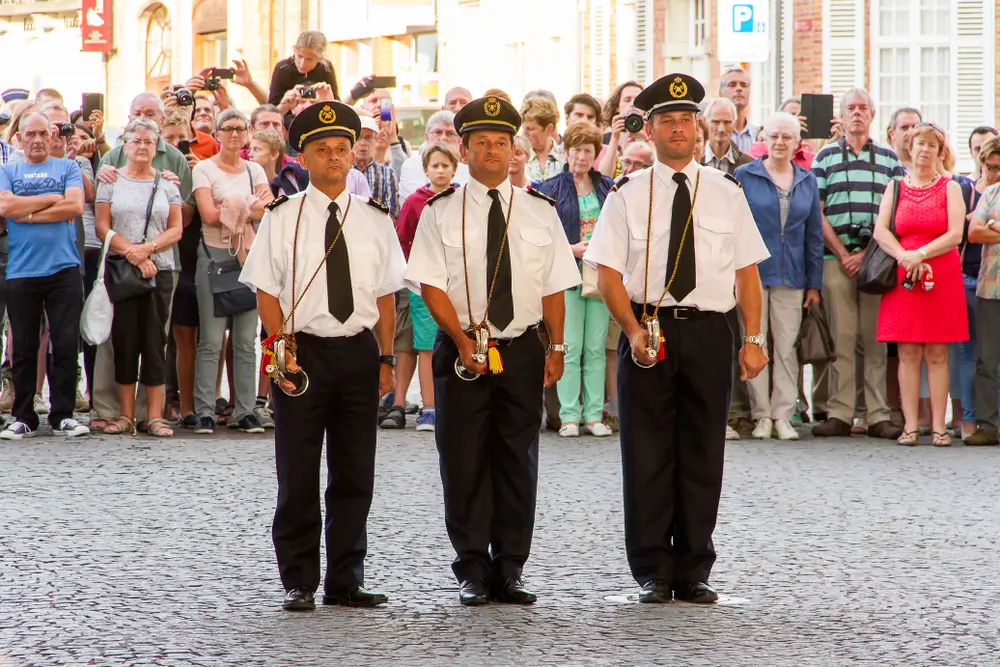 Trois agents de secours en uniforme lors d'une cérémonie officielle de remise de diplômes devant une foule.