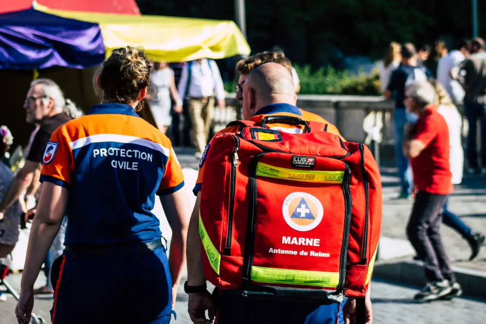 Agents de la protection civile belge en tenue technique avec sac de secours lors d'une mission de sauvetage.