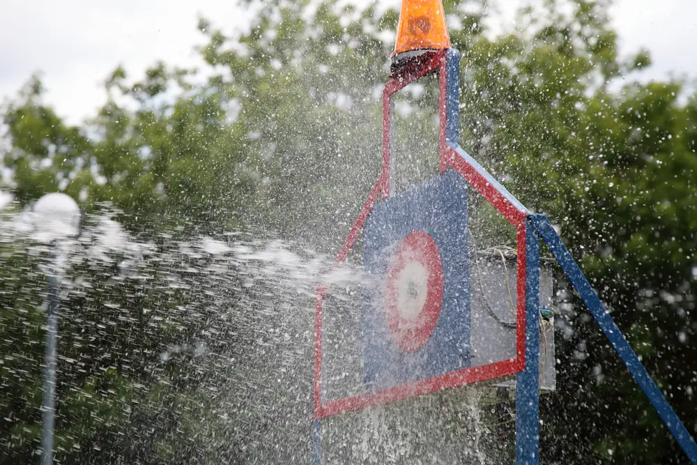 Jet d'eau frappant une cible de précision dans un centre de formation de pompiers lors d'un exercice technique.