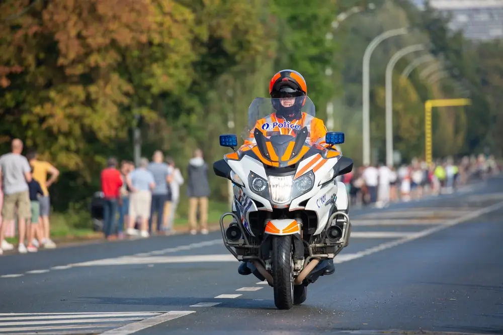 Agent de la protection civile belge à moto en intervention d'urgence sur une route pour sécuriser le terrain.