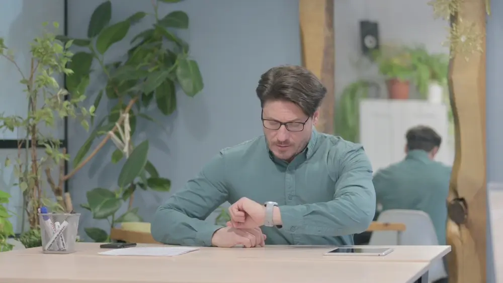 Candidat consultant sa montre avec concentration pour gérer son temps sous la pression d'un examen chronométré.