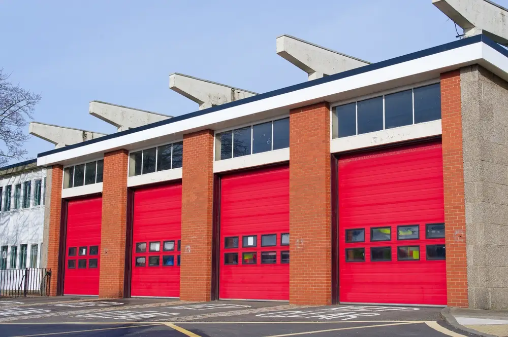 Caserne de secours avec quatre grandes portes rouges pour les camions et véhicules d'intervention.