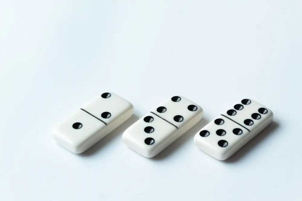 Trois dominos blancs alignés illustrant le format des tests de raisonnement logique et des jeux de dés.