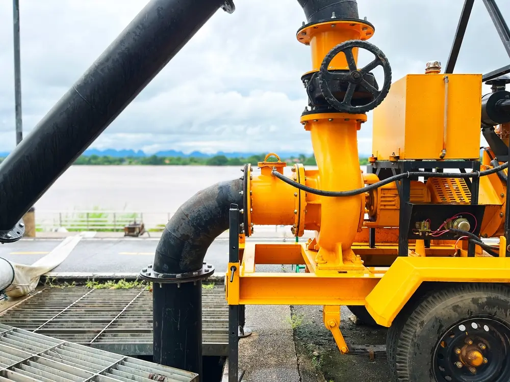 Pompe à eau industrielle jaune haute capacité déployée pour le pompage d'urgence lors d'inondations majeures.