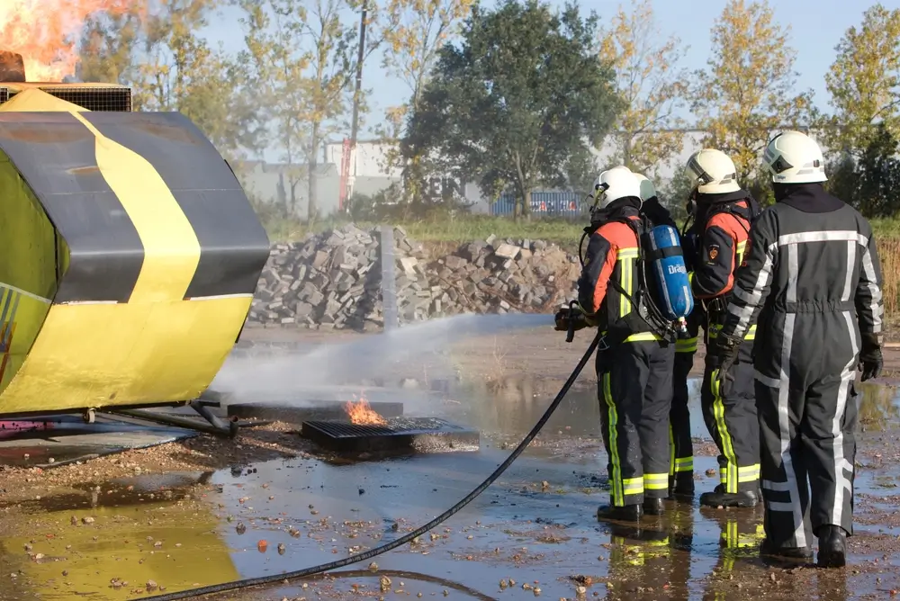 Futurs agents de secours en formation maîtrisant un incendie lors d'un exercice pratique dans une école du feu.