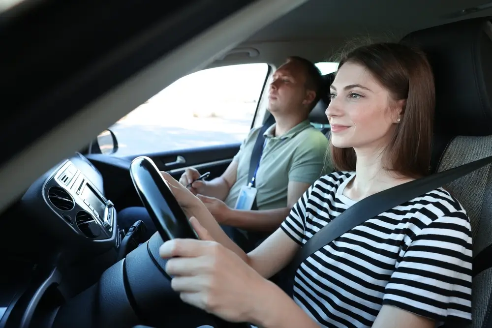 Candidate au volant d'une voiture d'auto-école avec un examinateur lors de son examen pour le permis de conduire B.