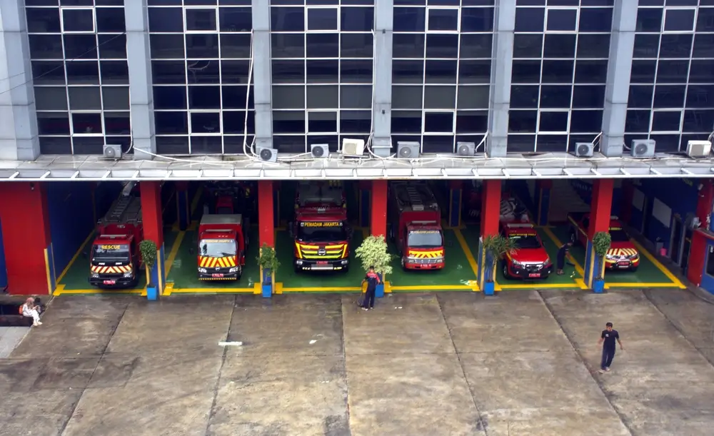Camions de pompiers et véhicules de secours stationnés dans le dépôt d'une caserne d'intervention.