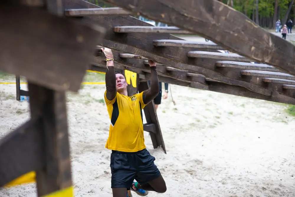 Recrue franchissant un parcours d'obstacles en bois lors d'un test physique d'aptitude pour la Protection civile.