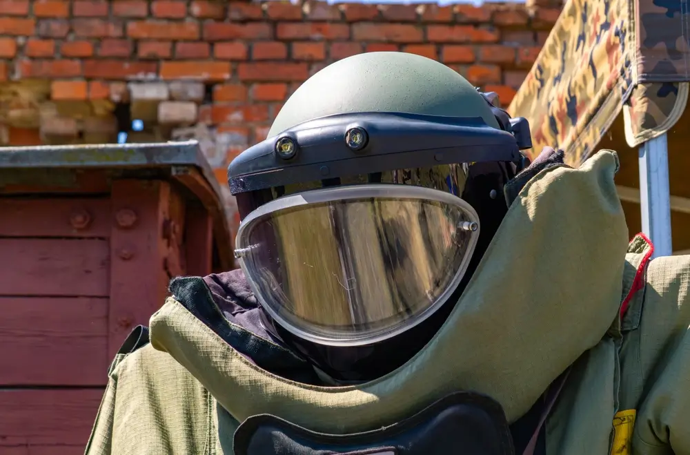 Démineur en combinaison de protection EOD avec casque à visière renforcée pour la neutralisation d'engins explosifs.