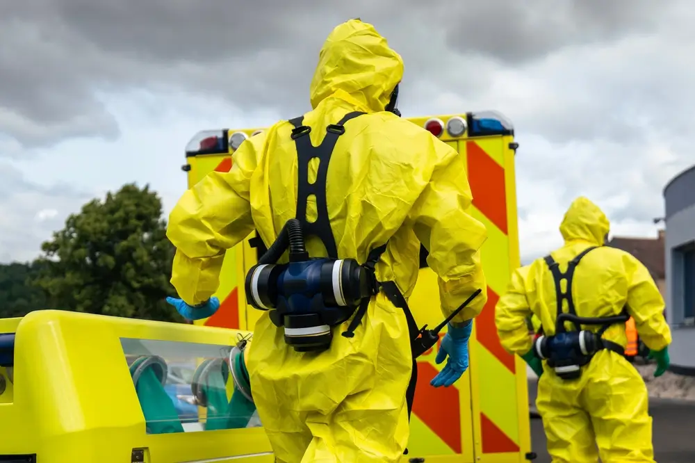 Deux agents en combinaison de protection NRBC jaune et masque respiratoire lors d'un exercice de formation.