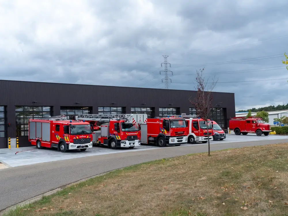 Véhicules d'intervention rouges alignés devant le bâtiment moderne d'une caserne de secours.