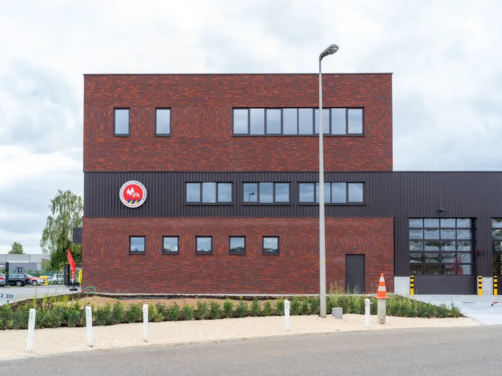 Bâtiment moderne d'une caserne de pompiers en briques rouges, lieu des épreuves de recrutement en zone de secours.