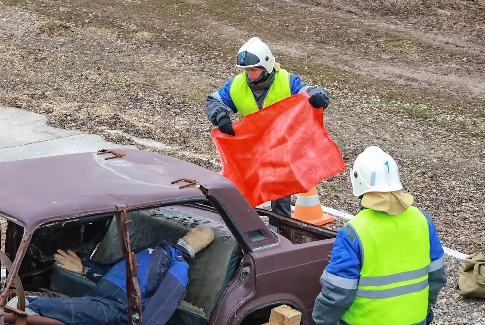 Agents de secours en plein exercice de formation au sauvetage routier sur une voiture accidentée avec un mannequin.