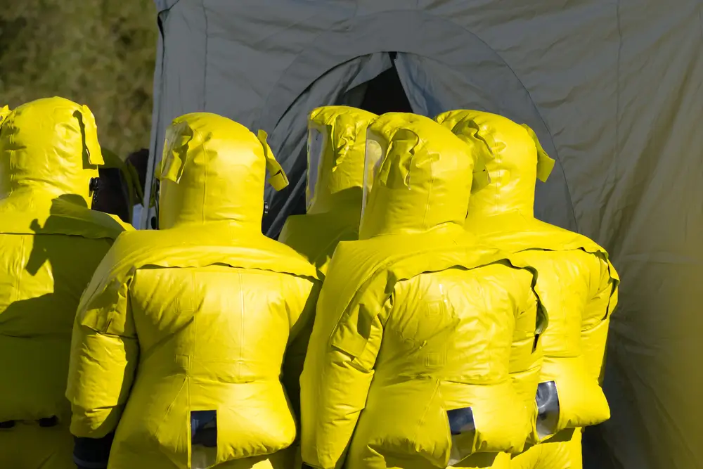 Équipe de la protection civile en combinaisons hazmat jaunes lors d'une intervention spécialisée de type CBRN.